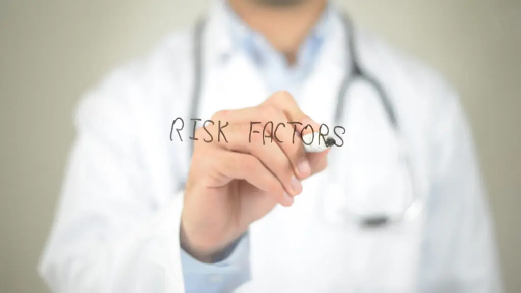 doctor writing "risk factors" on glass