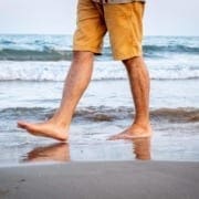 man walking on beach showing only legs