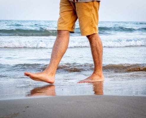 man walking on beach showing only legs
