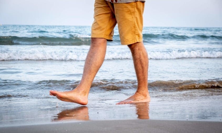 man walking on beach showing only legs