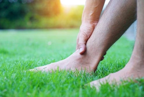 man holding ankle sitting in grass