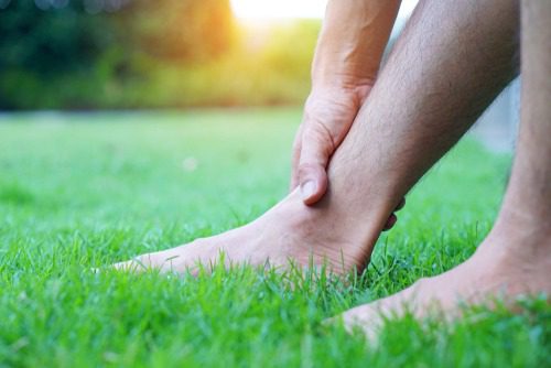 man holding ankle sitting in grass