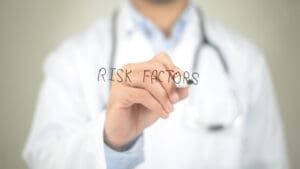 doctor writing "risk factors" on glass